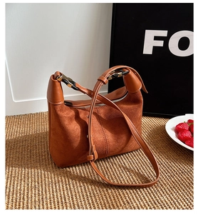 Close-up of brown suede crescent bag with smooth leather trim and gold hardware details