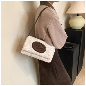 Detail of white faux fur tote bag with brown leather logo and slim strap on shoulder