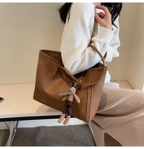 Detailed view of brown PU leather tote bag with a cute rabbit doll charm accessory