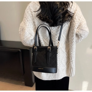 Detail einer schwarzen Stepp-Beuteltasche mit goldener Hardware und Modeschriftzug