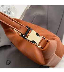 Close-up of golden metal buckle and zipper on a brown textured crescent bag