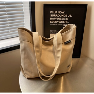 Vista macro del bolso tote de lona beige con etiqueta tejida de marca y textura duradera