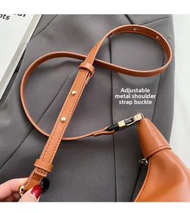 Close-up of brown PU leather crescent bag featuring adjustable strap with gold buckle