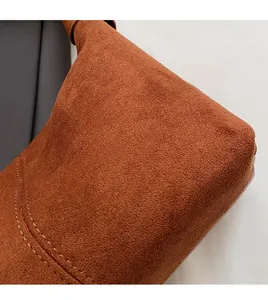 Macro detail of dark brown suede crescent bag showing premium fabric texture and stitching