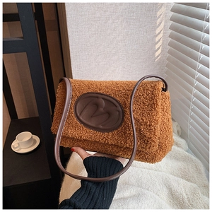 Detail view of plush brown faux fur handbag with leather logo patch and slim shoulder strap