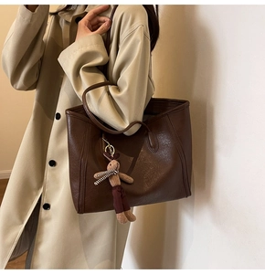 Detail of coffee brown tote bag with lychee texture leather and cute rabbit pendant