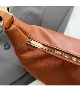 Detail of brown crescent bag showing smooth PU leather and suede with golden metal zipper