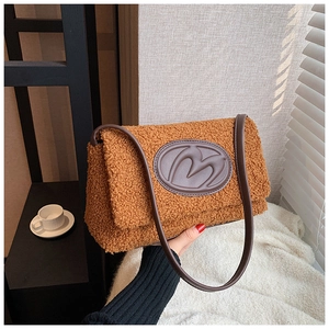 Detailed close-up of brown teddy plush handbag featuring an embossed M letter logo patch