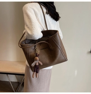 Close-up of deep brown leather tote bag with cute plush rabbit charm on shoulder strap