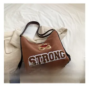 Close-up of brown suede bag with teddy bear patch, strong embroidery, and leather strap