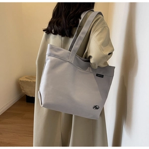 Detalle de bolso tote de lona gris claro con la etiqueta del logotipo y textura de la tela