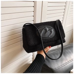 Detail view of plush black lamb wool tote bag with M letter embossed leather patch