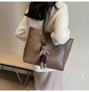 Close-up of brown vintage tote bag with rabbit charm on a stylish model outfit