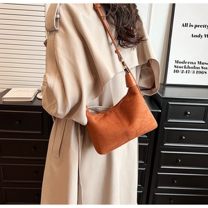 Detail of matte brown crescent bag with sleek leather strap and structural stitching