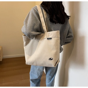 Primer plano del bolso tote de lona beige con gran capacidad y detalle de etiqueta tejida
