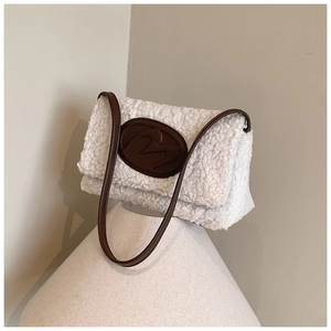 Close-up of white plush texture and brown leather logo detail on square shoulder bag