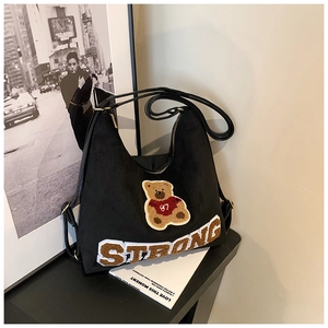 Detail of black suede tote bag with embroidered teddy bear and STRONG lettering