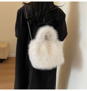 Détail du sac à bandoulière en fausse fourrure avec chaîne argentée sur manteau noir