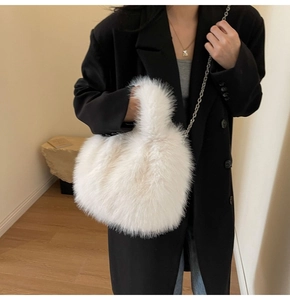 Détail d'un sac à main en fausse fourrure blanche douce porté sur un manteau noir
