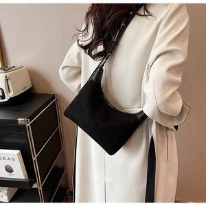 Close-up of minimalist black suede crescent bag with leather strap and zipper details