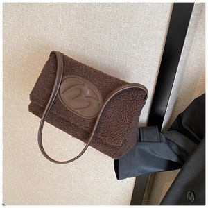 Macro detail of dark brown fuzzy plush tote with leather patch and embossed letter design