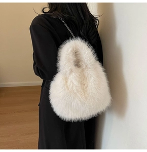 Détail de la texture en fausse fourrure blanc crème et fine chaîne en métal sur le sac