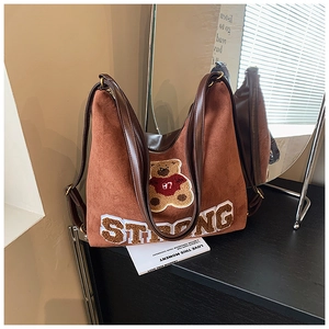 Detail of vintage brown suede tote bag with teddy bear embroidery and strong letter print