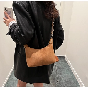 Chic caramel hobo bag in matte suede texture worn over the shoulder with leather jacket