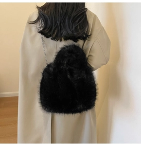 Détail du sac à bandoulière en fausse fourrure noire avec chaîne argentée sur modèle