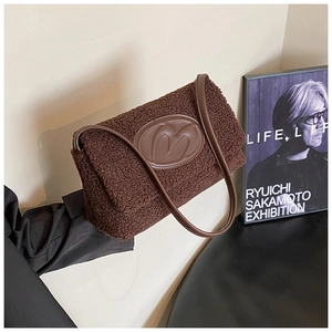 Detail of plush brown tote with leather M logo patch and soft faux shearling texture
