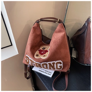 Detailed shot of brown frosted suede backpack featuring embroidered bear and strong letter patch