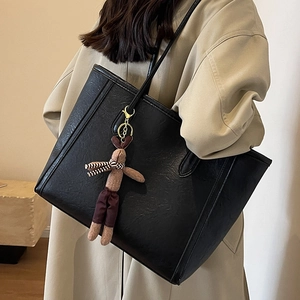 Large black faux leather tote bag with a cute brown rabbit plush charm and long shoulder straps