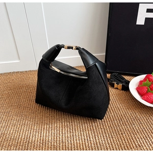 Macro detail of black suede and smooth leather crescent bag with gold zipper and hardware
