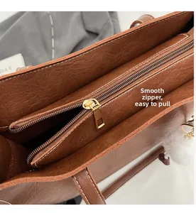 Détail de la fermeture éclair en métal doré lisse sur un grand sac cabas en cuir marron
