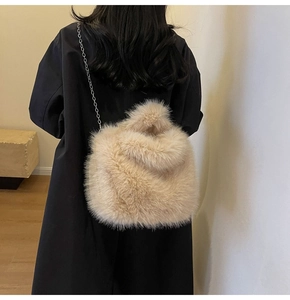 Vue détaillée du sac seau en peluche beige avec chaîne argentée sur manteau noir