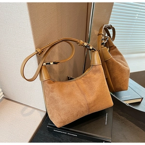 Detail of brown matte suede hobo bag with gold hardware on a vintage book