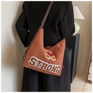 Detail of brown vintage frosted leather bag with plush bear patch on female model