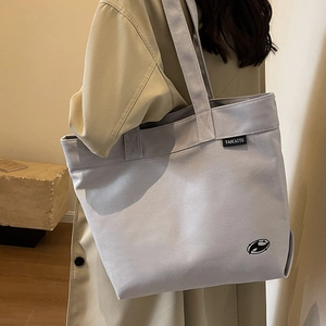Bolso tote de lona gris claro minimalista con correa al hombro en un entorno de estilo