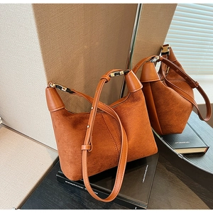 Detailed side view of brown matte suede hobo bag on books showing adjustable strap