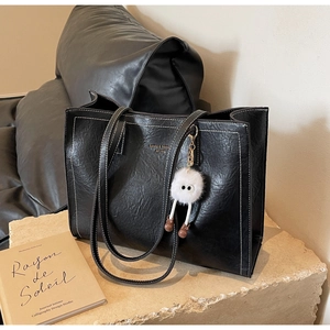 Détail du sac cabas noir avec surpiqûres blanches et charme de monstre en peluche