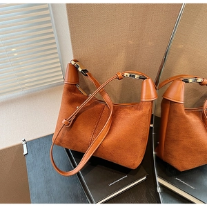 Detail of brown suede crescent bag showing matte texture and metallic hardware