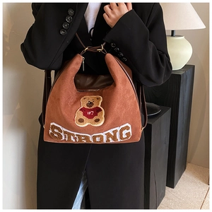 Detail of a brown suede bag featuring a cute bear patch and STRONG embroidery detail