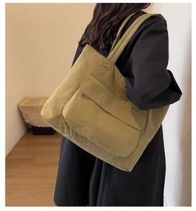 Detail of olive green canvas tote bag featuring a large front flap pocket for commuting