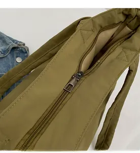 Detail of smooth metal zipper and khaki lining on olive green quilted tote bag