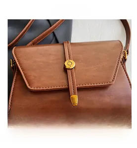 Détail du sac bandoulière en cuir PU marron avec boucle dorée et coutures soignées