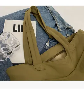 Detail of khaki nylon tote bag with reinforced stitching and smooth metal zipper closure
