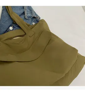 Detail of olive green nylon tote bag showing durable stitching and soft fabric texture