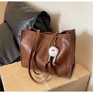 Détail du sac cabas vintage en cuir marron avec surpiqûres blanches et charme peluche