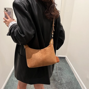 Brown suede crescent shoulder bag with stitching detail worn with black leather jacket