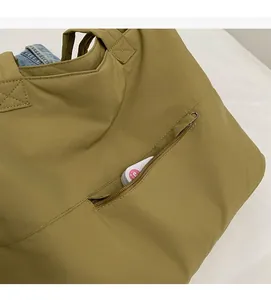 Detail of the front zipper pocket and reinforced stitching on a khaki nylon tote bag